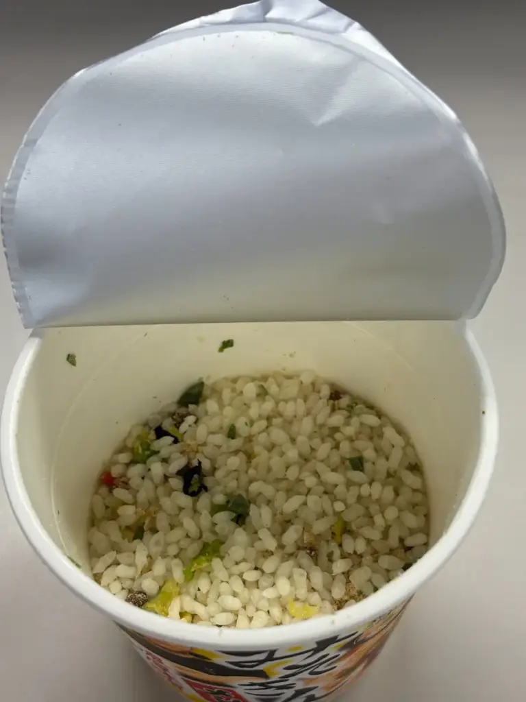 新みそきんメシのフタを半分開けた状態。中には乾燥ごはんとかやくがたっぷり入っている。