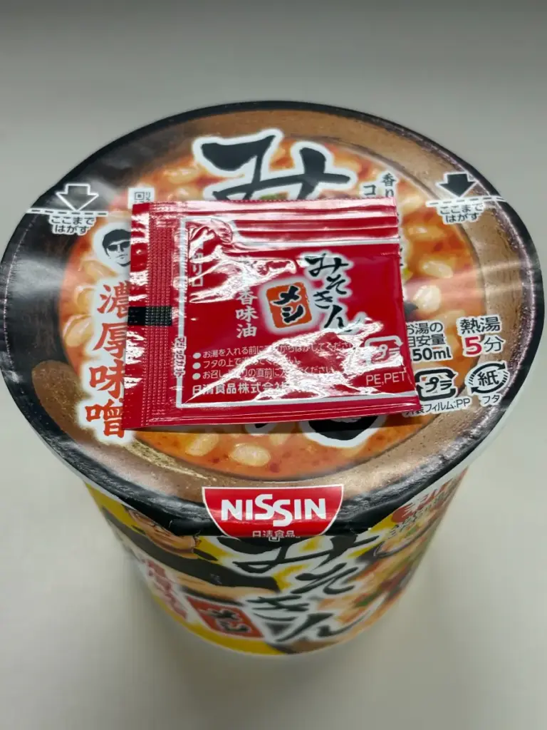 新みそきんメシのフタの上に特製香味油の小袋を置いて温めている様子。