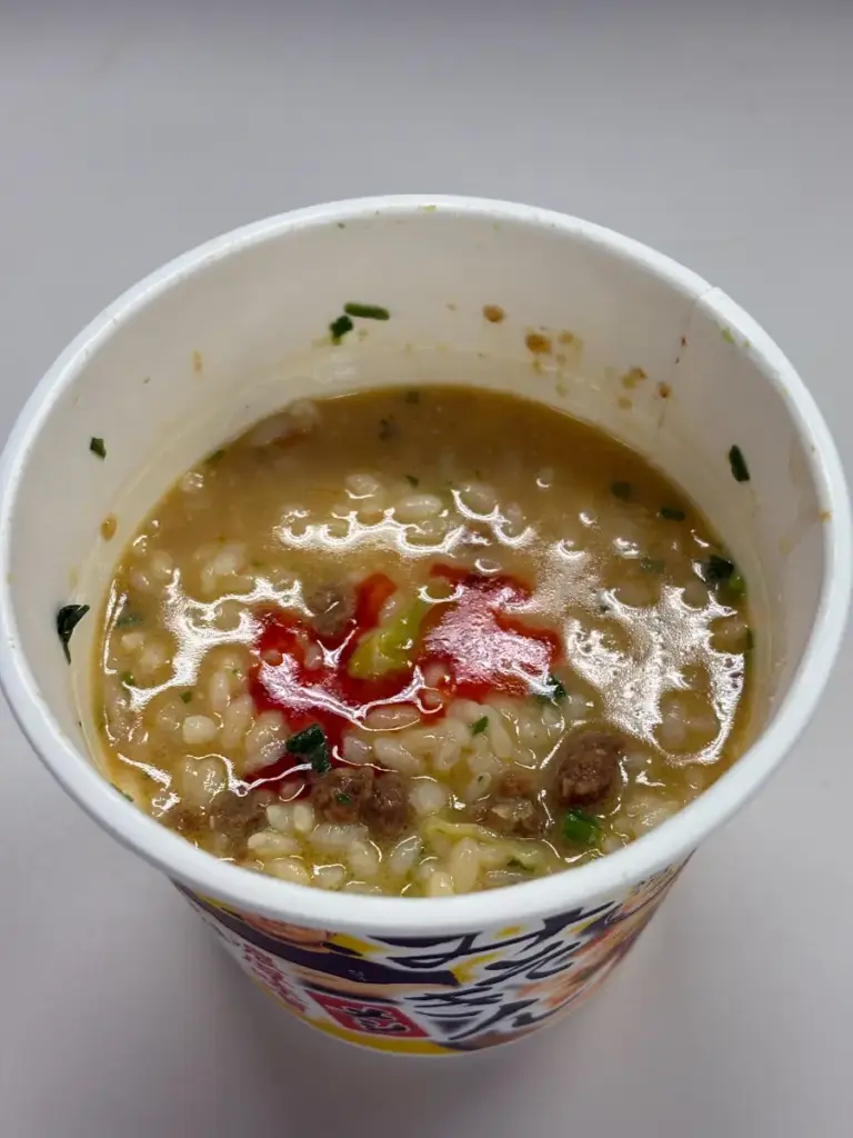 温めた香味油を新みそきんメシに注いでいる様子。黄金色の油がスープに広がっている。