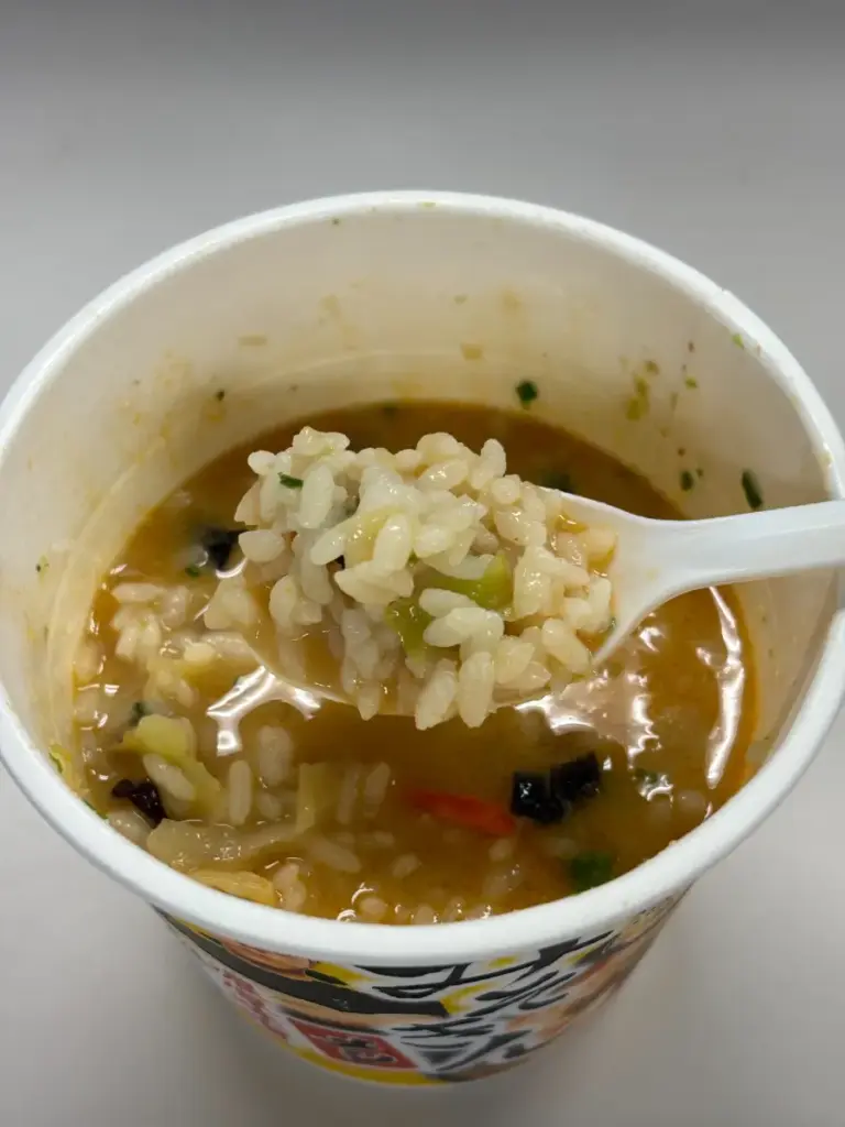 新みそきんメシをスプーンですくい上げた様子。ごはん粒にスープがよく絡んでいる。